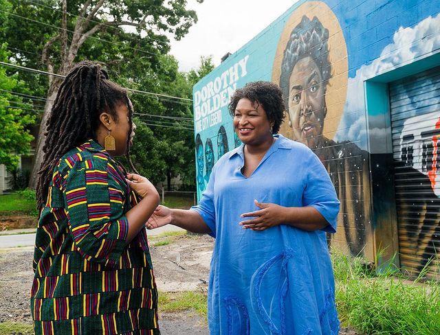 Stacey Abrams stands near the Dorothy Bolden Mural